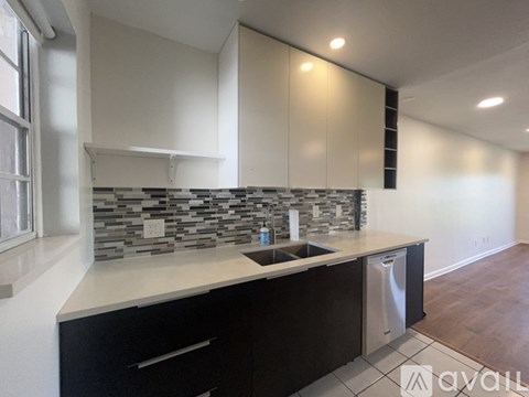 A kitchen with black cabinets and a stone backsplash.