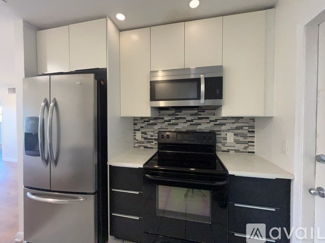 A kitchen with a stainless steel refrigerator and black stove top oven.