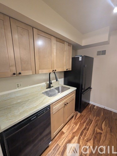 A kitchen with wooden cabinets and a black refrigerator.