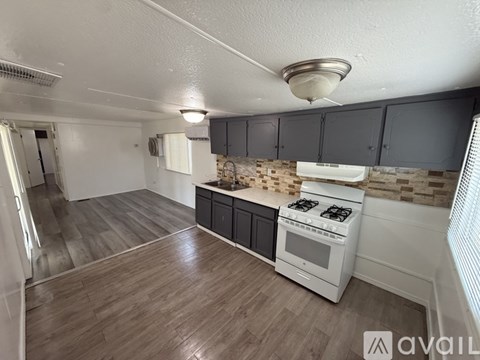 A kitchen with a stove, cabinets, and a tiled backsplash.