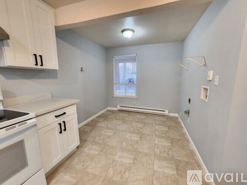 A kitchen with white cabinets and a tiled floor.