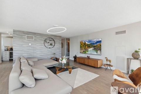A living room with a grey sofa, a coffee table, and a painting on the wall.