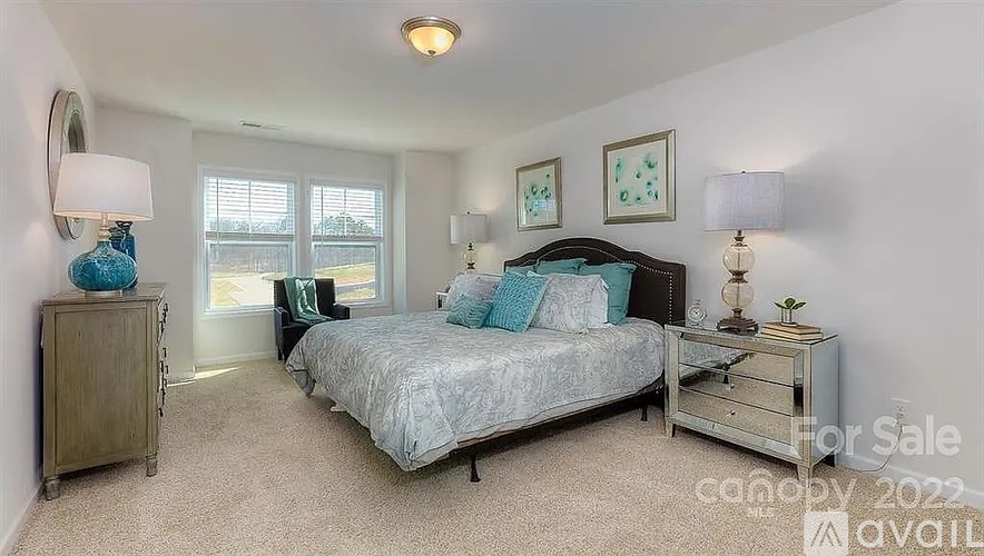 A bedroom with a bed, nightstand, and lamp is for sale.