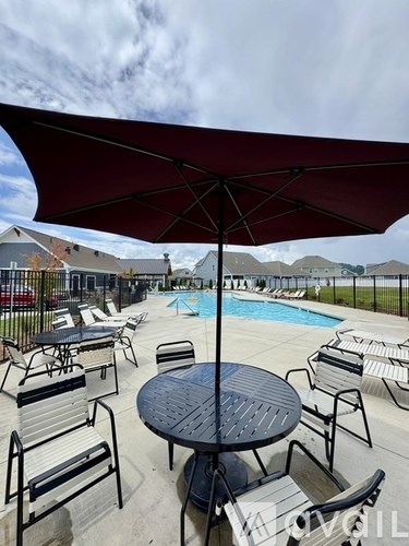 A poolside area with a table and chairs under an umbrella.