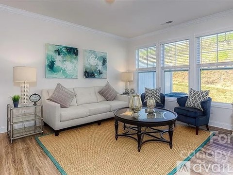 A living room with a white couch, a blue chair, and two abstract paintings on the wall.