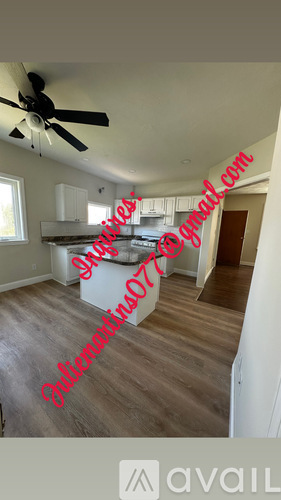 A room with a ceiling fan and wooden flooring.