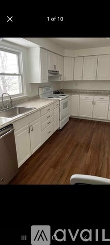 A kitchen with white cabinets and a wooden floor.