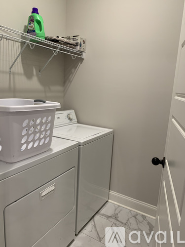 A laundry room with a washer and dryer and a basket on top of the washer.