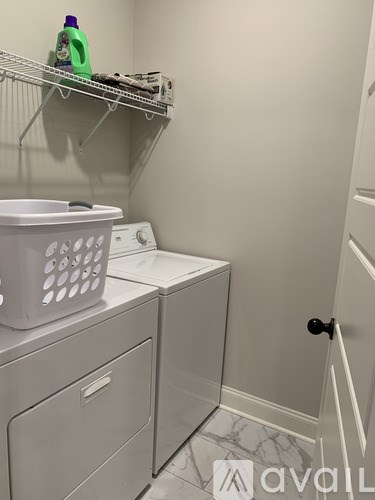 A laundry room with a washer and dryer and a basket on top of the washer.