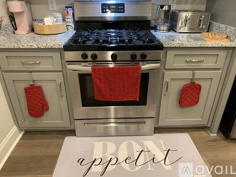 A kitchen with a stove top oven and a red towel hanging on it.
