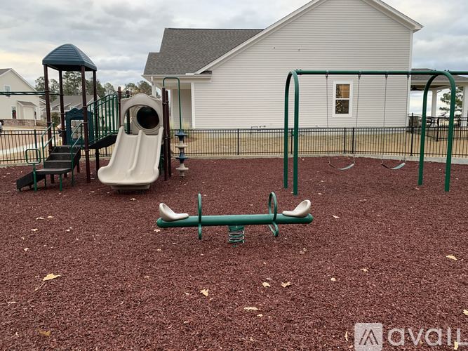 A playground with a slide, swings, and a seesaw.