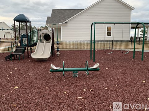 A playground with a slide, swings, and a seesaw.
