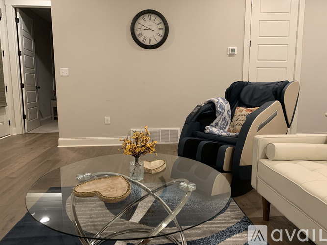 A living room with a glass table and a clock on the wall.