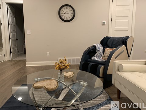 A living room with a glass table and a clock on the wall.