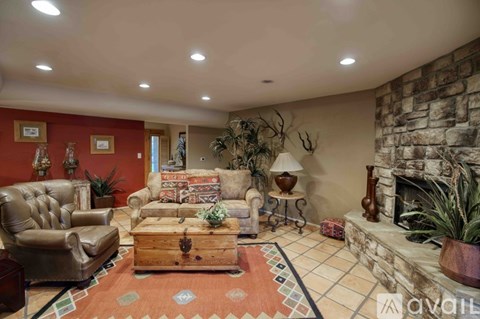A living room with a stone fireplace and a rug on the floor.