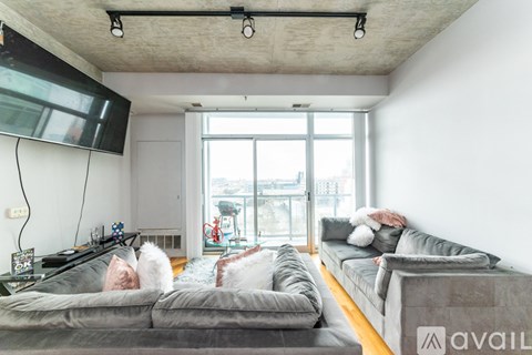 A living room with grey couches and a flat screen TV mounted on the wall.