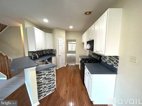 A kitchen with white cabinets and a black countertop.