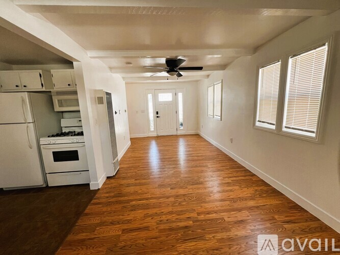A kitchen with white appliances and wooden floors.