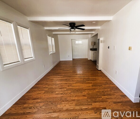 A long hallway with wood floors and a ceiling fan.