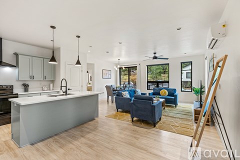 A modern kitchen with a blue couch in the living room.