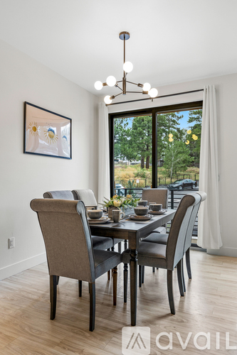 A dining room with a table set for two and a view of the backyard.