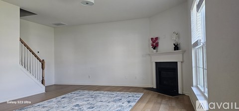 A living room with a fireplace and a rug on the floor.