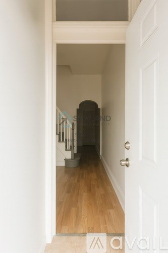 A hallway with a white door and a wooden floor.