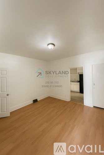 A room with wooden flooring and a wall that says "SKYLAND DEVELOPMENT" and a phone number.