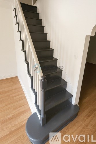 A staircase with a grey base and black steps with white handrails.