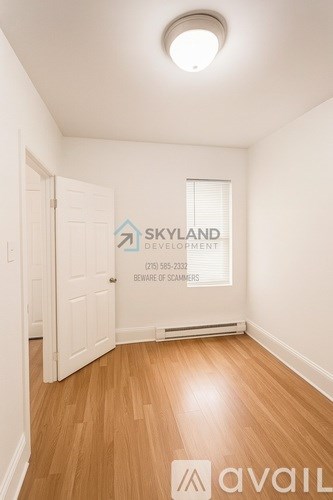 A room with wooden floors and a doorway leading to another room.
