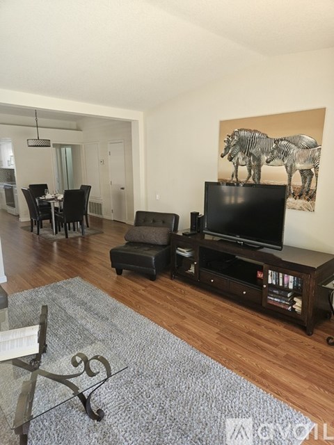 A living room with a grey rug and a television.