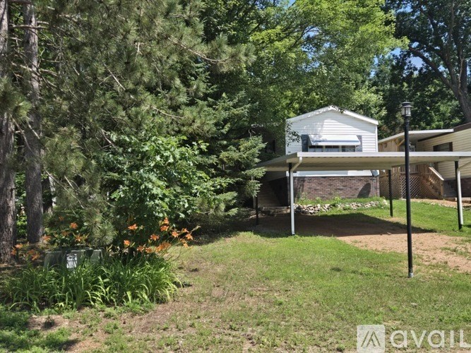 A house with a white roof is surrounded by greenery and trees.