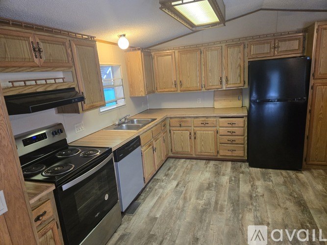 A kitchen with wooden cabinets and a black refrigerator.