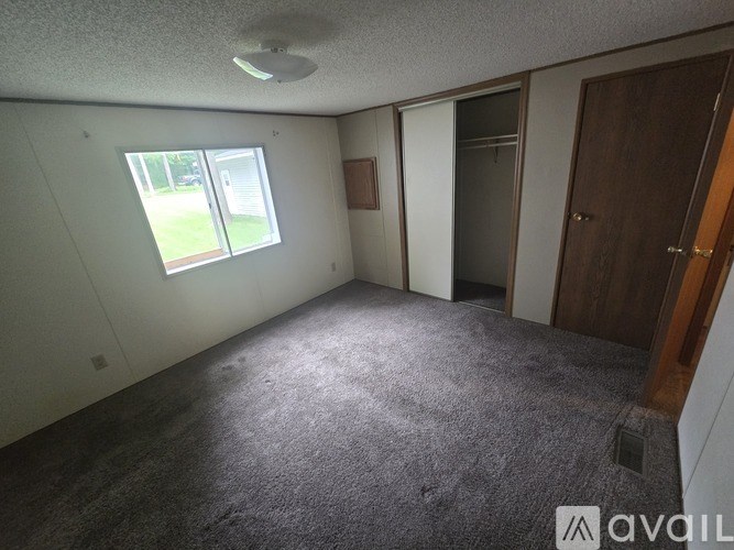 A room with a carpeted floor, a window, and a door.