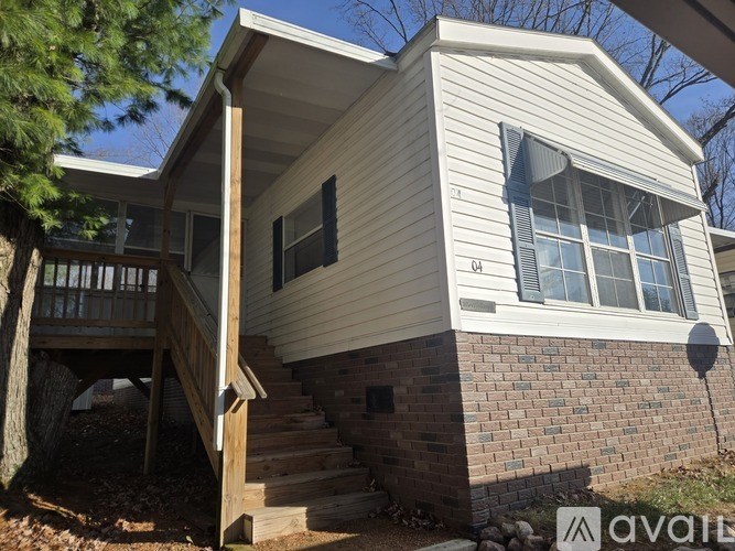 A house with a wooden deck and a brick base.