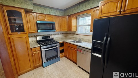 A kitchen with wooden cabinets and a black refrigerator.
