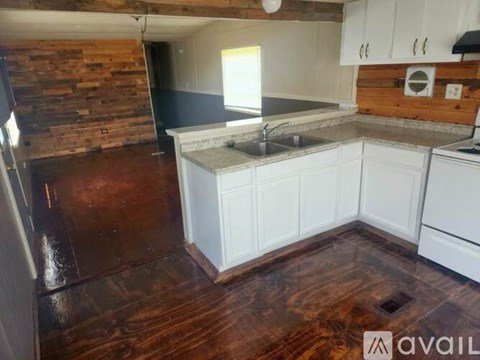 A kitchen with white cabinets and a wooden wall.