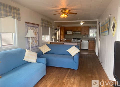 A living room with blue couches and a ceiling fan.