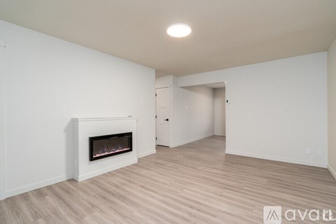 A spacious room with a fireplace and wooden flooring.