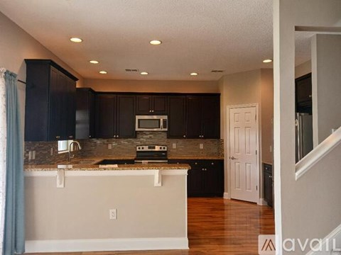 A kitchen with dark brown cabinets and a granite countertop.