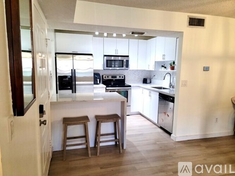 A kitchen with white cabinets and a wooden floor.