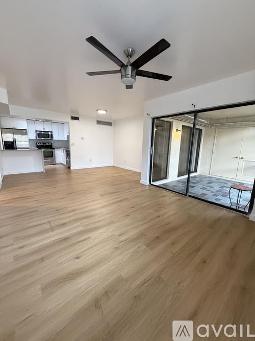 A spacious room with wooden flooring and a ceiling fan.