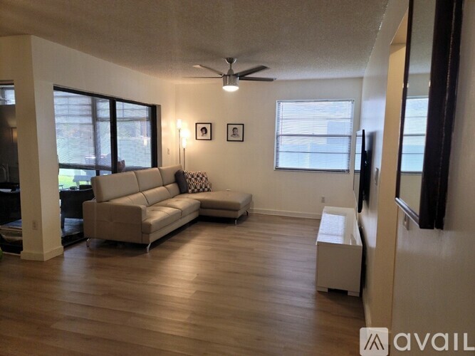 A living room with a couch, a television, and a ceiling fan.