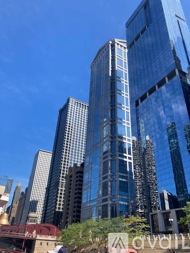 A tall glass building stands in front of other buildings on a sunny day.