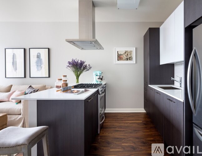 A kitchen with a refrigerator, stove, and a table with a vase of flowers on it.