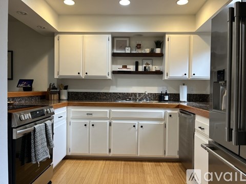 A modern kitchen with white cabinets and stainless steel appliances.