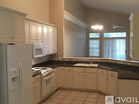A kitchen with white cabinets and black countertops.