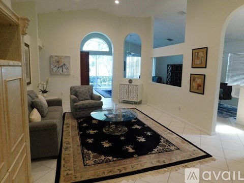 A living room with a rug in the center and a grey couch to the left.