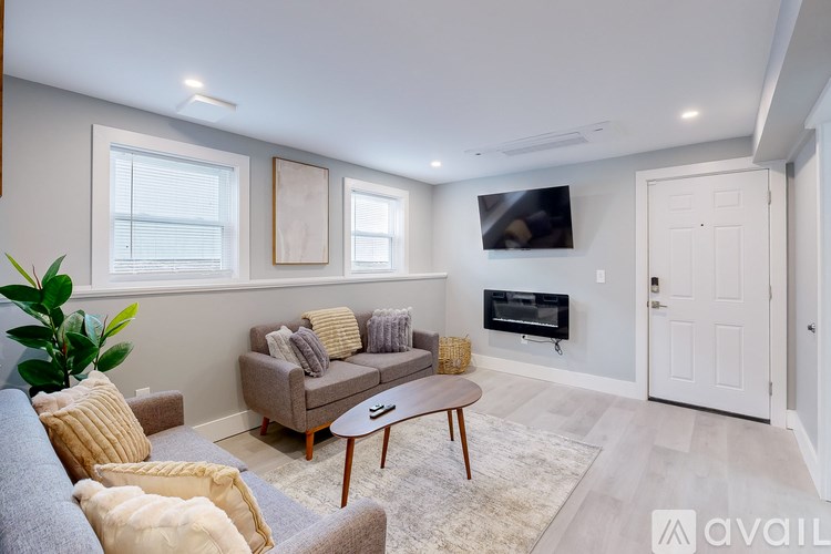 A living room with a grey couch, a brown coffee table, and a flat screen TV mounted on the wall.