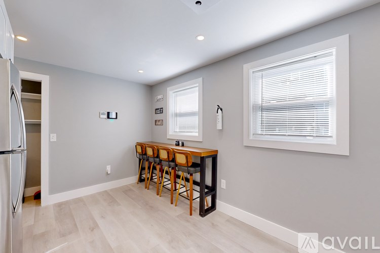 A kitchen with a refrigerator, a table with chairs, and a window with blinds.